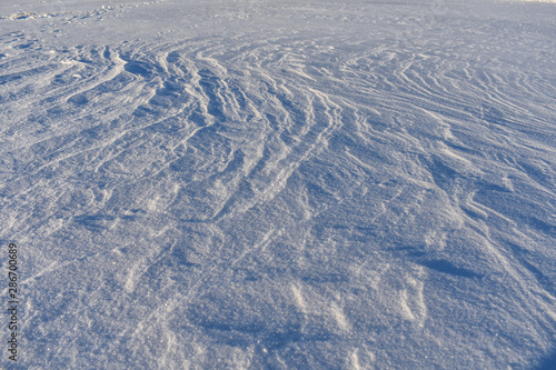 Snow on a frozen lake blown by wind creating a pattern.