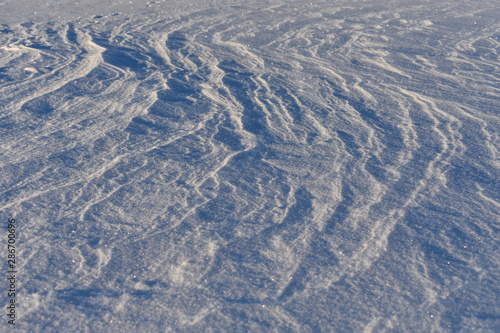 Snow on a frozen lake blown by wind creating a pattern.