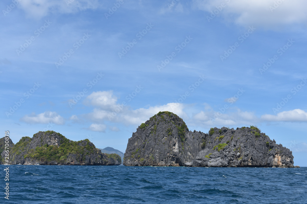 Small rock formations and blue waters and sky.