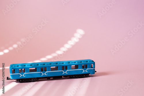 Model of a Russian metro car on a pink background with sunlight. Russian transport. Toy model