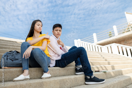boy and girl friend teenagers summer student angry at each other while tutoring the summer exam bok at the stairs in the park