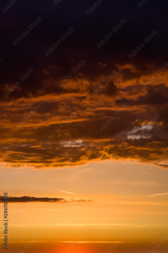 Stormy dramatic sky background with yellow red and orange clouds. Sunset skyline. Storm on the beach. Vertical size