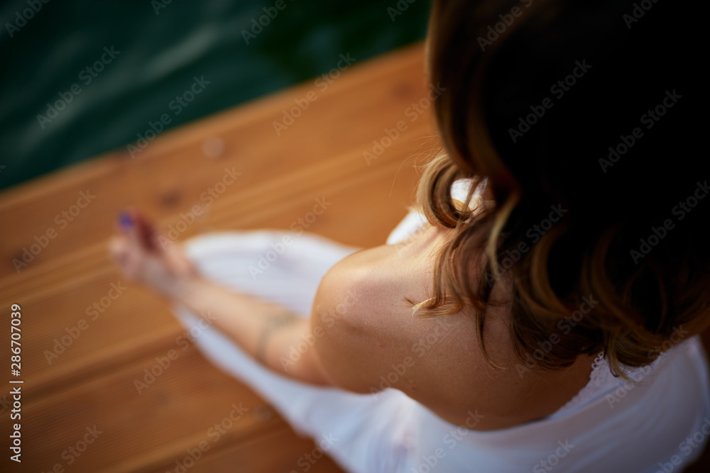 Φωτογραφία Top view of Caucasian woman sitting on pier in lotus position and meditating