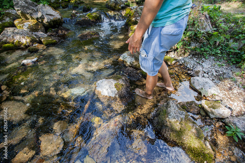 Man crossing the stream barefoot