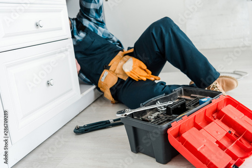 Canvas-taulu selective focus of repairman working near kitchen cabinet and toolbox
