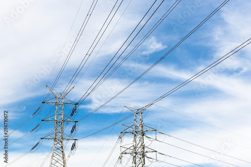 Power pylons standing on partly cloudy afternoon.