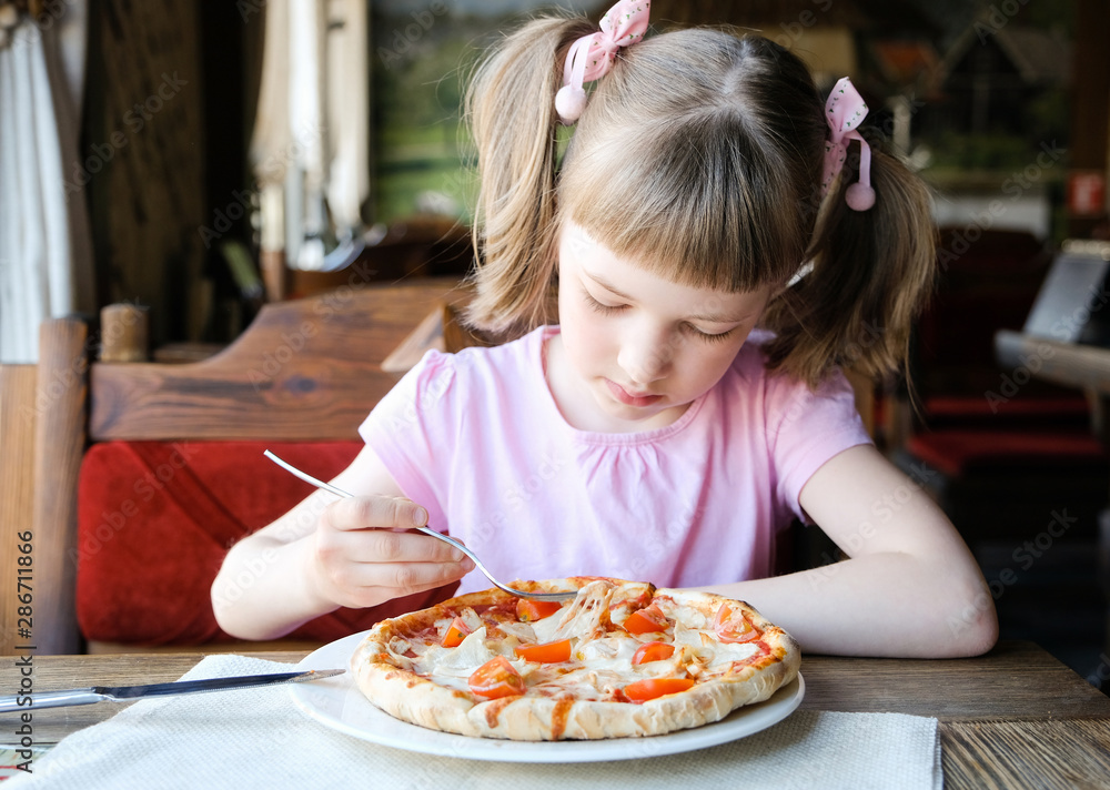 Serious little girl eats pizza