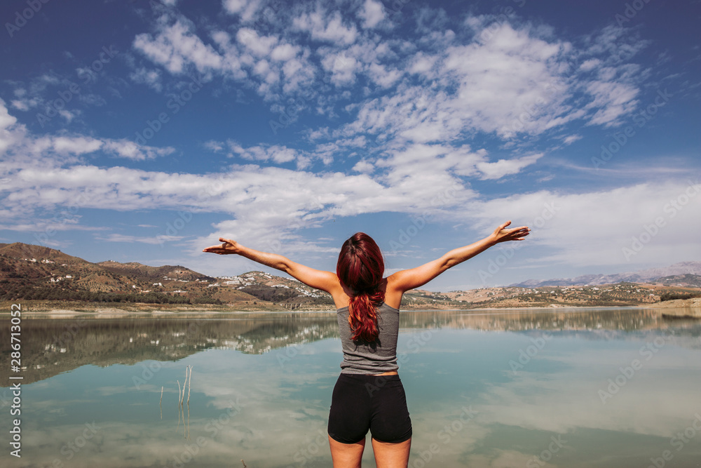 happy woman opens her arms in front of a lake on a trip with much happiness happy woman opens her arms in front of a lake on a trip with much happiness