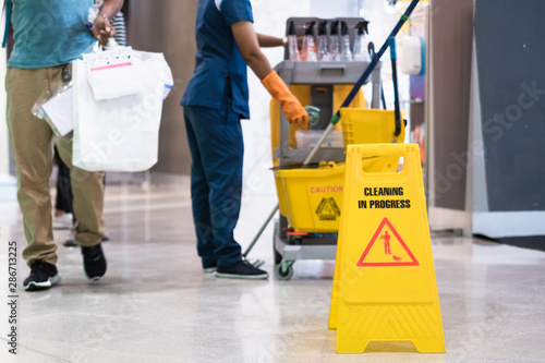 Tablou pe pânză Janitor Cleaning Floor In Front Of Yellow Caution Cleaning in progress