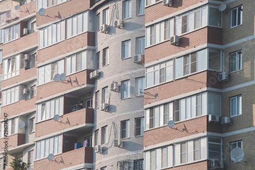 Close-up. High-rise windows with air conditioning and balconies. The concept of overpopulation of planet.