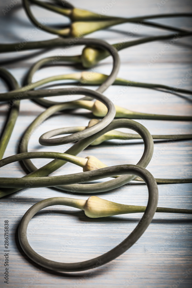 Ripe garlic arrows on a light wooden background. Toned Ripe garlic arrows on a light wooden background. Toned