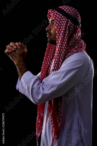 An arab man is praying on black background