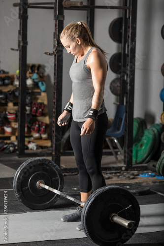 Young powerful woman preparing for deadlift in gym