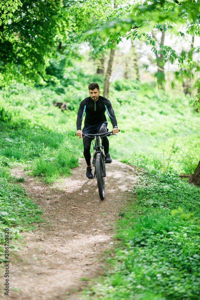 Mountain bike cyclist riding single track outdoor with green park on background
