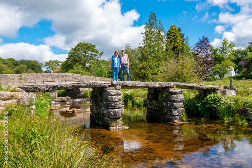 Senior couple standing on ancient clapper bridge at Postbridge, Dartmoor National Park, Devon, England photo