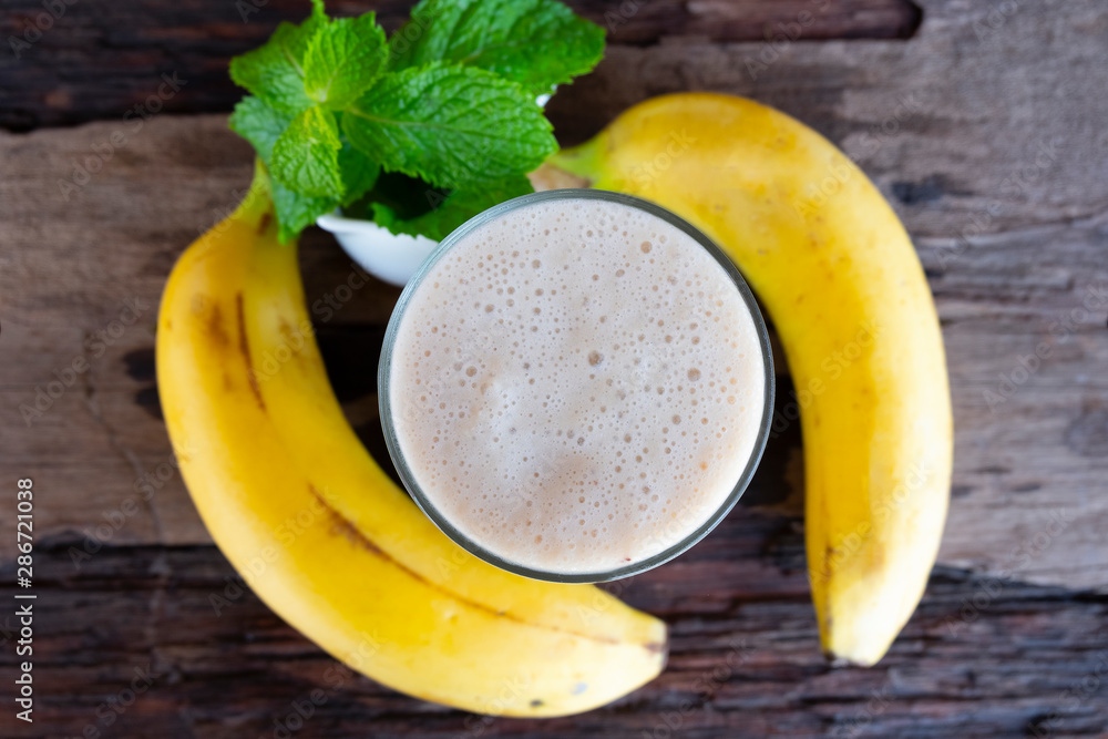Banana fresh cocktail vanilla smoothies juice white fruit beverage healthy the taste yummy In glass for milkshake on wooden background from top view. Banana fresh cocktail vanilla smoothies juice white fruit beverage healthy the taste yummy In glass for milkshake on wooden background from top view.