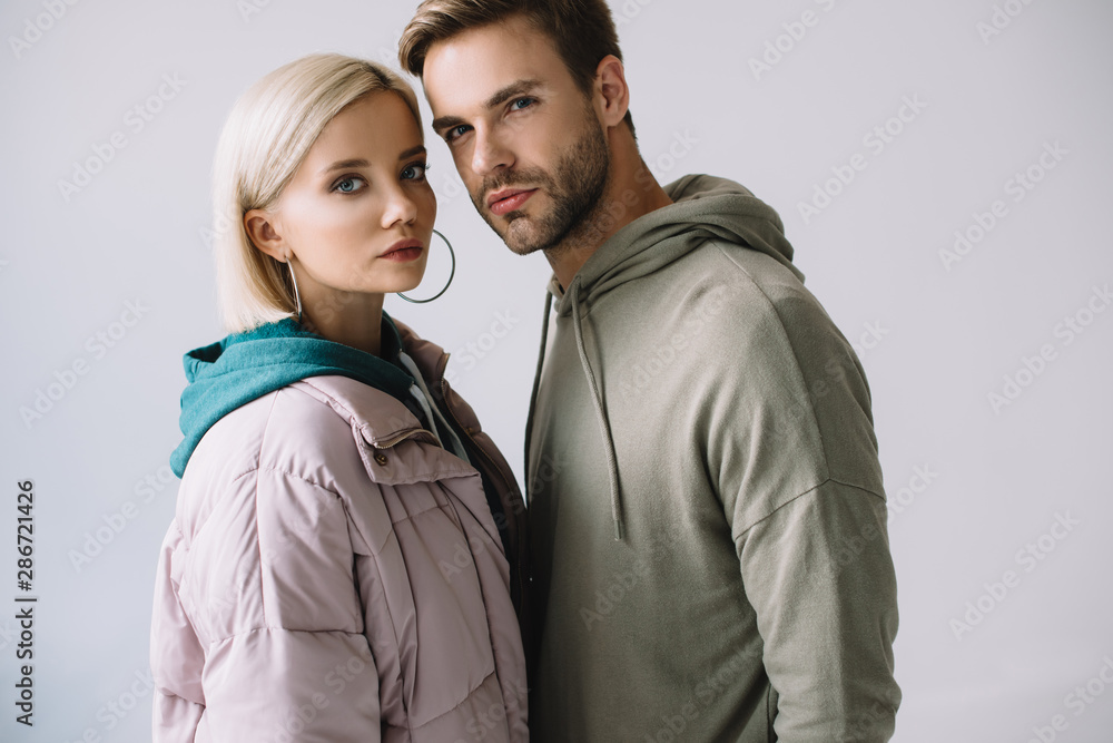 stylish blonde girl and bearded man in autumn outfits looking at camera isolated on grey stylish blonde girl and bearded man in autumn outfits looking at camera isolated on grey
