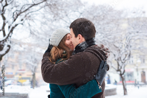 Young loving couple dressed in plaid scarves walk at the old city in winter. Hugging and kissing © cenchild