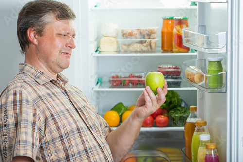 mature men at fridge with green apple