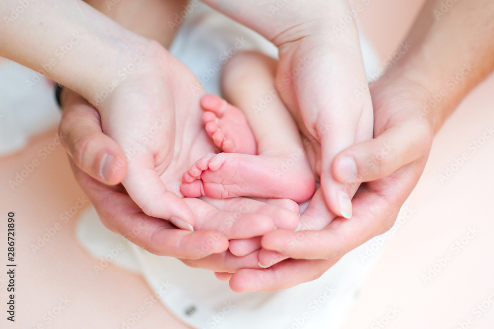 hands of father and mother gently support the feet of a newborn baby hands of father and mother gently support the feet of a newborn baby