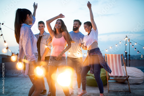 Happy friends with drinks toasting at rooftop party at night photo