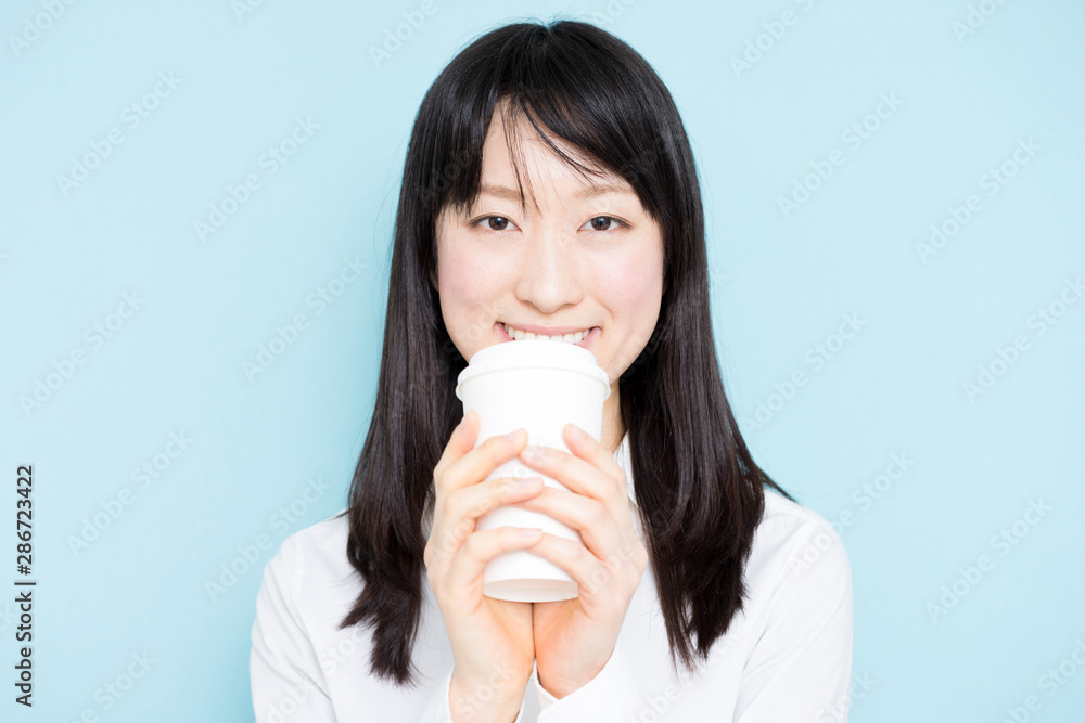 Young business woman drinking coffee against light blue background Young business woman drinking coffee against light blue background
