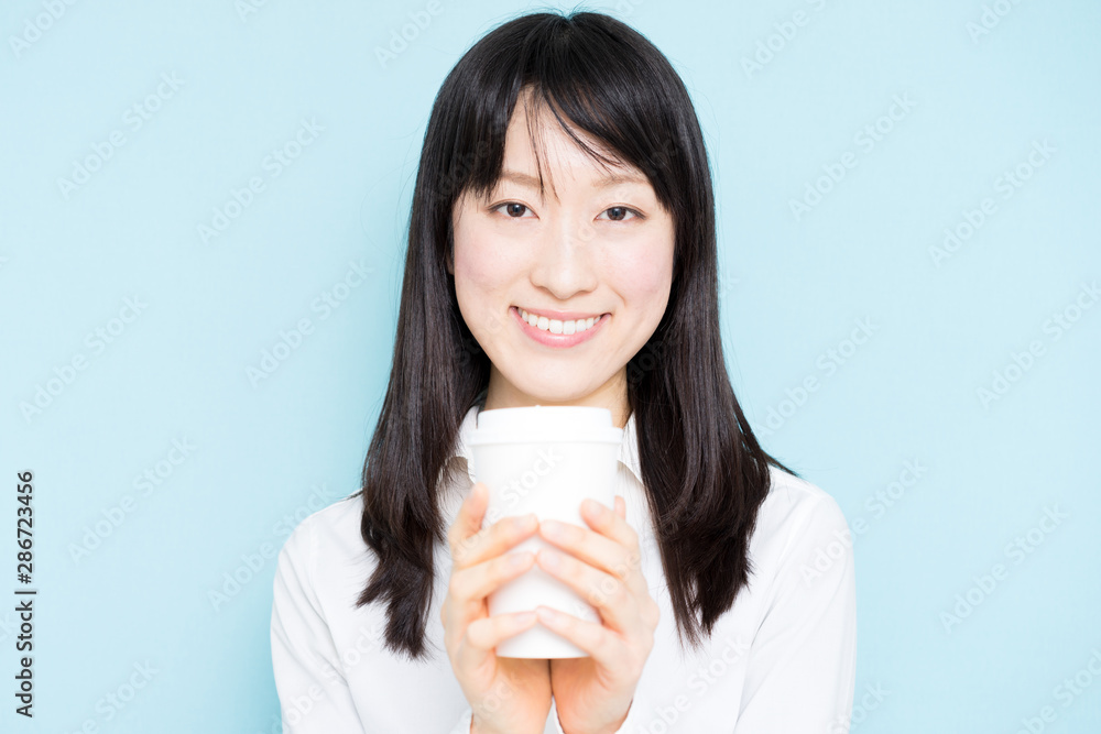 Young business woman drinking coffee against light blue background Young business woman drinking coffee against light blue background