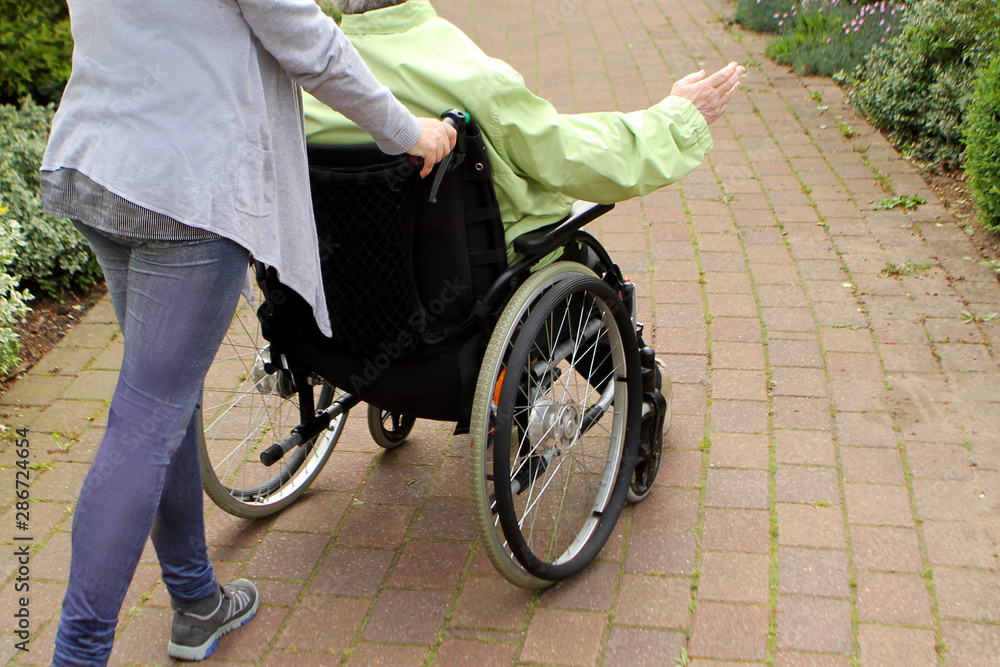 Fototapeta premium woman in a disabled person's park driving an elderly woman, rear view, horizon shifted to give a dynamic picture