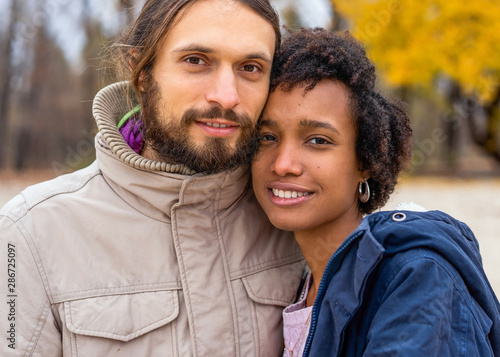 guy with an african american girl in love in autumn park makes her an offer to get married