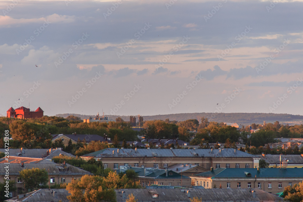 Naklejka premium Small soviet city on sunset.The sun comes out from behind the clouds.