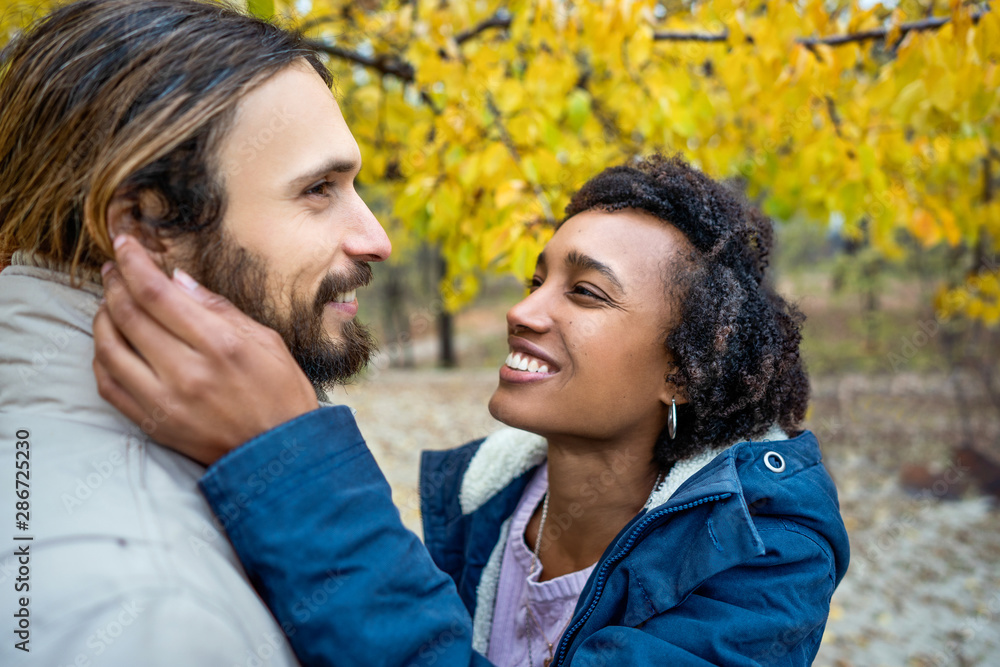 guy with an african american girl in love in autumn park makes her an offer to get married