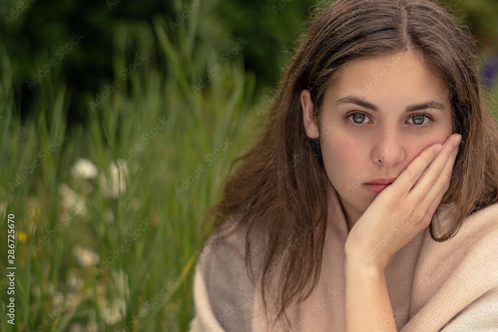 Emotion concept. A young unhappy woman sitting in a park. Burnout and depression. Emotion concept. A young unhappy woman sitting in a park. Burnout and depression.