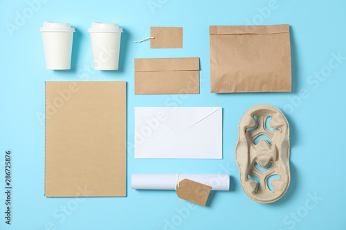 Flat lay. Paper cups and office supplies on blue background, copy space