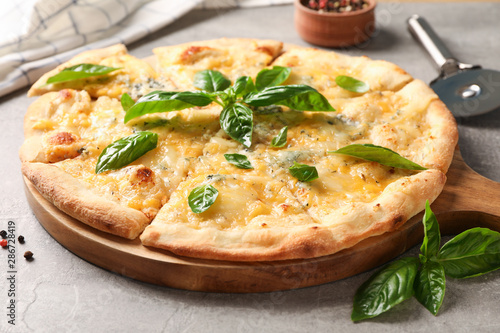 Cheese pizza with basil, cutter and spices on grey background, close up