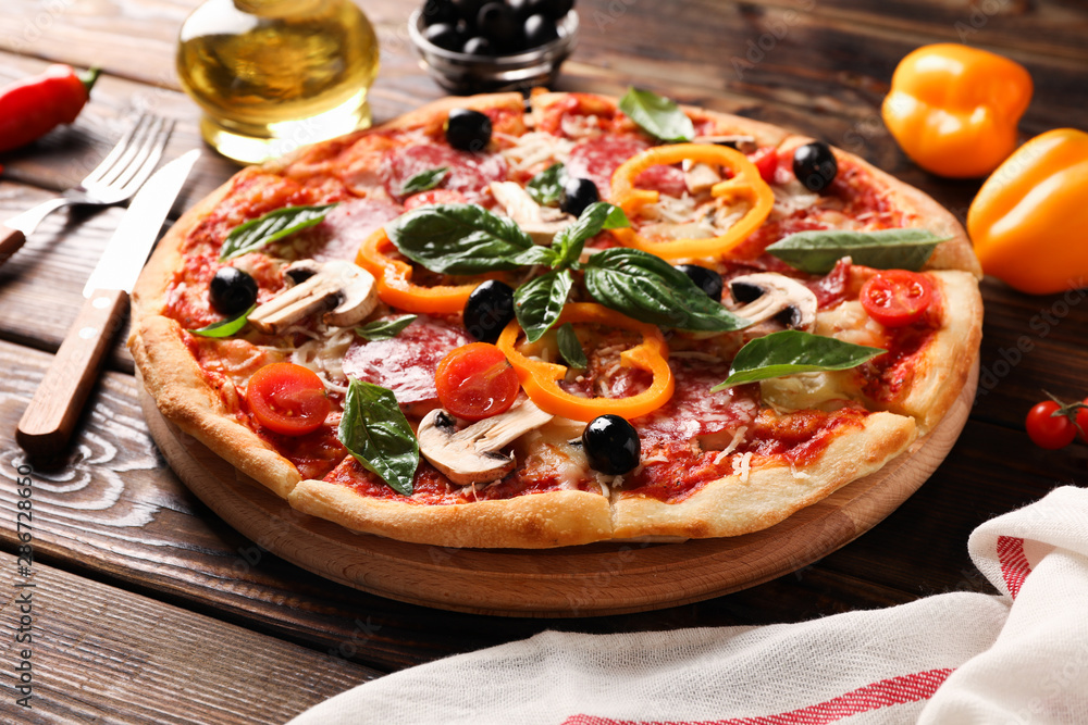 Delicious pizza and ingredients on wooden background, close up