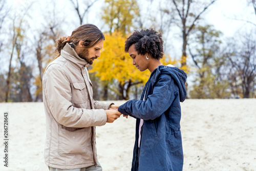 guy with an african american girl in love in autumn park makes her an offer to get married