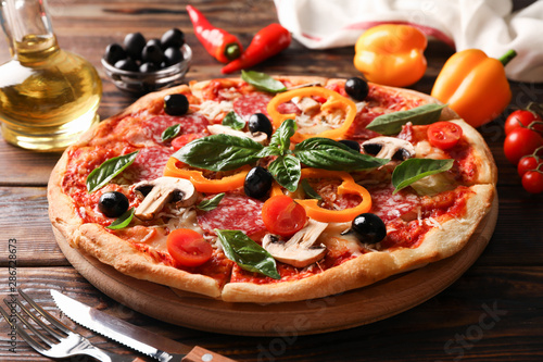 Delicious pizza and ingredients on wooden background, close up