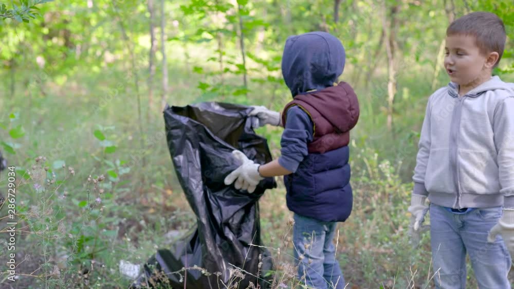 A group of women and children collect garbage in the forest. Volunteers collect plastic and other waste in black plastic bags. People are responsible for the environment. A group of women and children collect garbage in the forest. Volunteers collect plastic and other waste in black plastic bags. People are responsible for the environment.