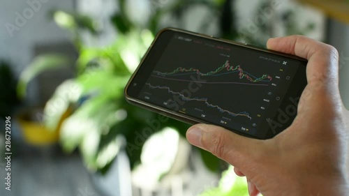 Bitcoin market, crypto trading online, trader working with a mobile phone on cryptocurrency exchange. Man touching screen, browsing market data, chart. Crypto currency. Bitcoin cryptocurrency.