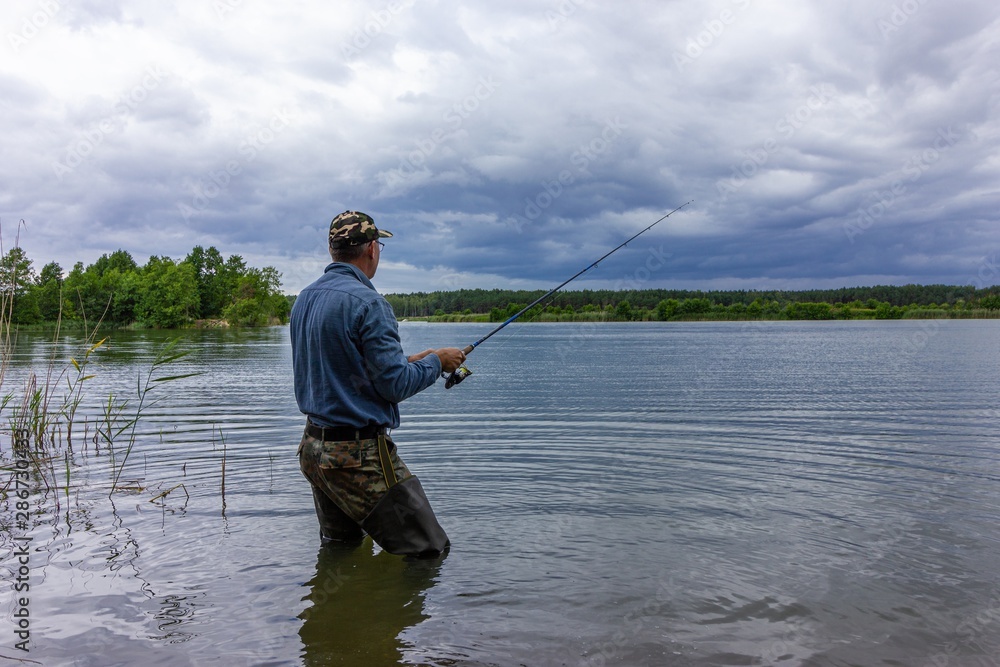 angler standing on the lake shore during cloudy day angler standing on the lake shore during cloudy day