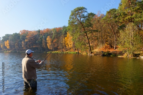 angler catching the fish at sunny autumnal day