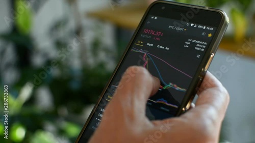 Bitcoin market, crypto trading online, trader working with a mobile phone on cryptocurrency exchange. Man touching screen, browsing market data, chart. Crypto currency. Bitcoin cryptocurrency.