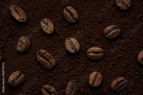 whole coffee beans on top of ground coffee close up. top view