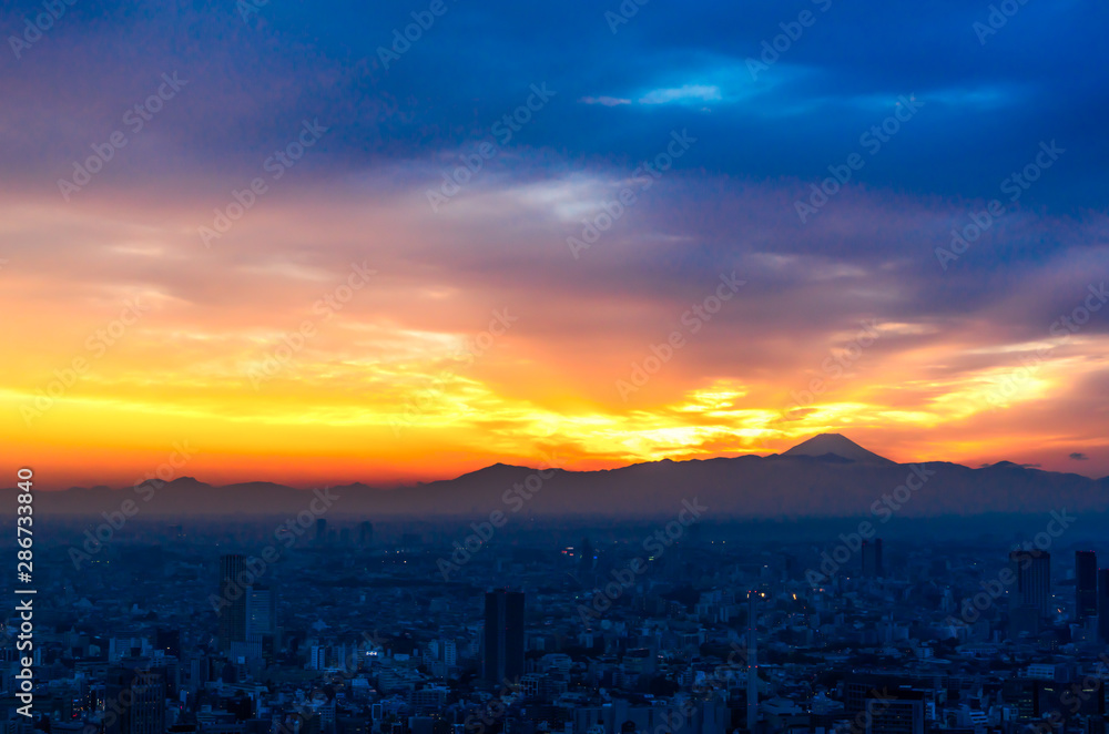 The sun sets over the cityscape of Tokyo, with Mount Fuji in the far distance view from Mori tower , roppongi hills , tokyo