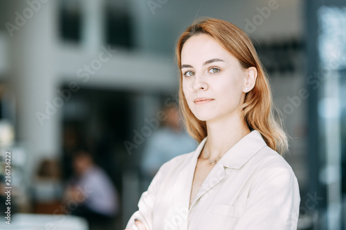 Free Download business portrait of a young girl on the background of the office. working situation with a smiling woman. - GFXLoad