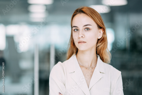 business portrait of a young girl on the background of the office. working situation with a smiling woman.