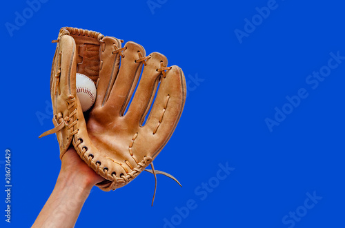 Картината върху платно Hand in a leather baseball glove caught a ball on a blue background