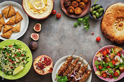 Assorted variety of Arabic and Middle Eastern food on a dark rustic background. Hummus,tabbouleh salad, Fattoush salad,pita,meat kebab,falafel,baklava. Frame of Arabian dishes.Top view,copy space