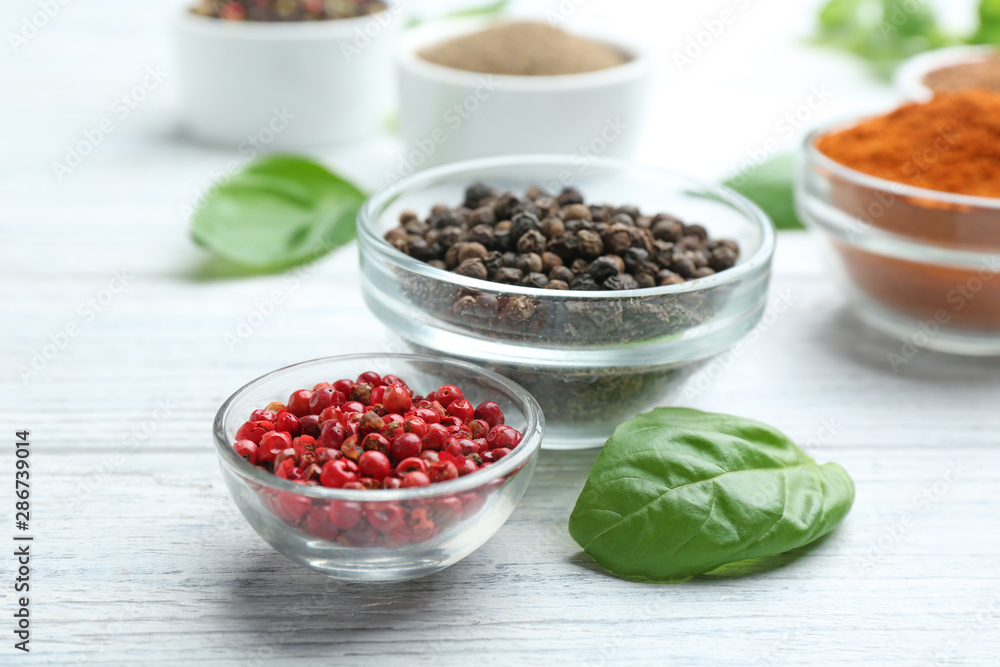 Glass bowls of red and black pepper corns on white wooden table Glass bowls of red and black pepper corns on white wooden table