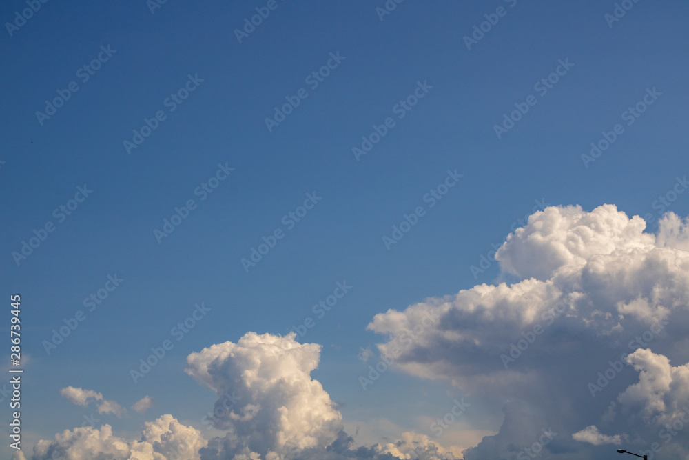Dense and soft clouds in the open sky on a summer day, and foreground road lights and slightly blurred power lines Dense and soft clouds in the open sky on a summer day, and foreground road lights and slightly blurred power lines